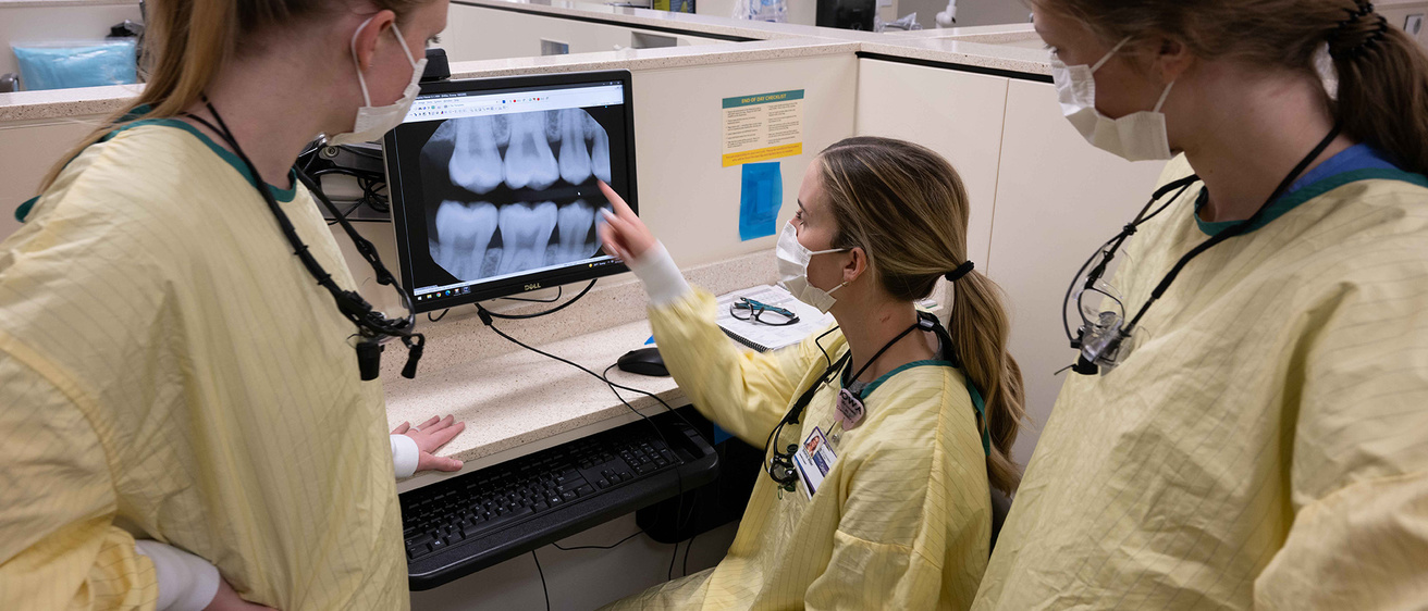 Three women dental students examining an x-ray